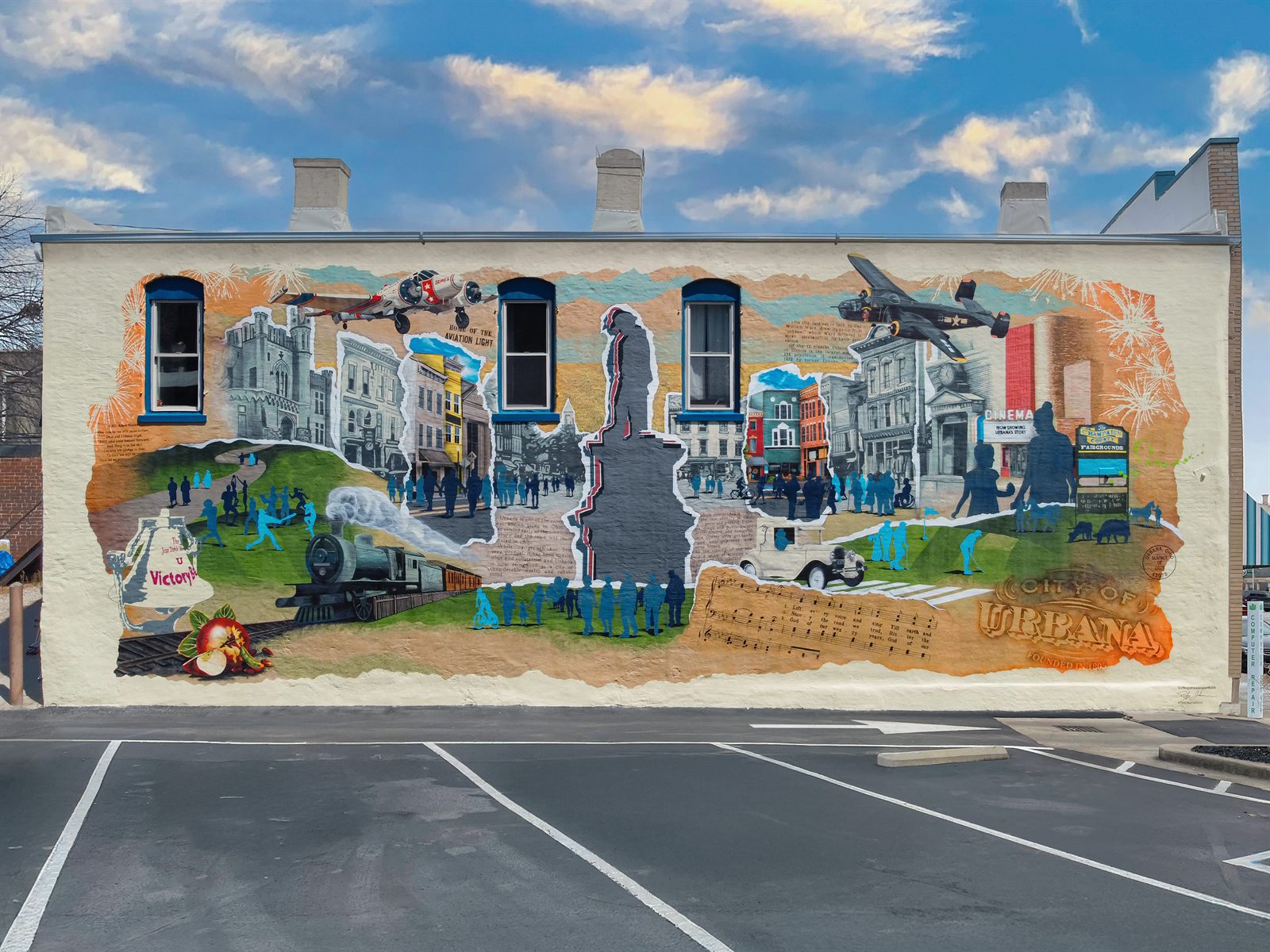The finished Urbana Mural by Studio Roo, a painted collage of the town's history covering the once-blank wall