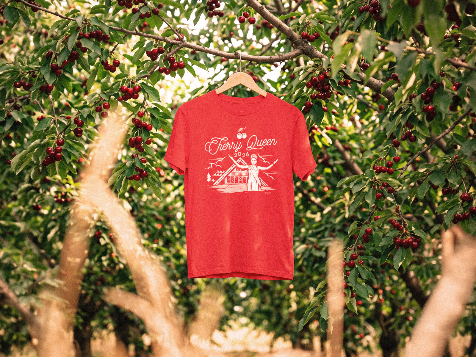 National Cherry Queen 2026 shirt hanging in a cherry orchard