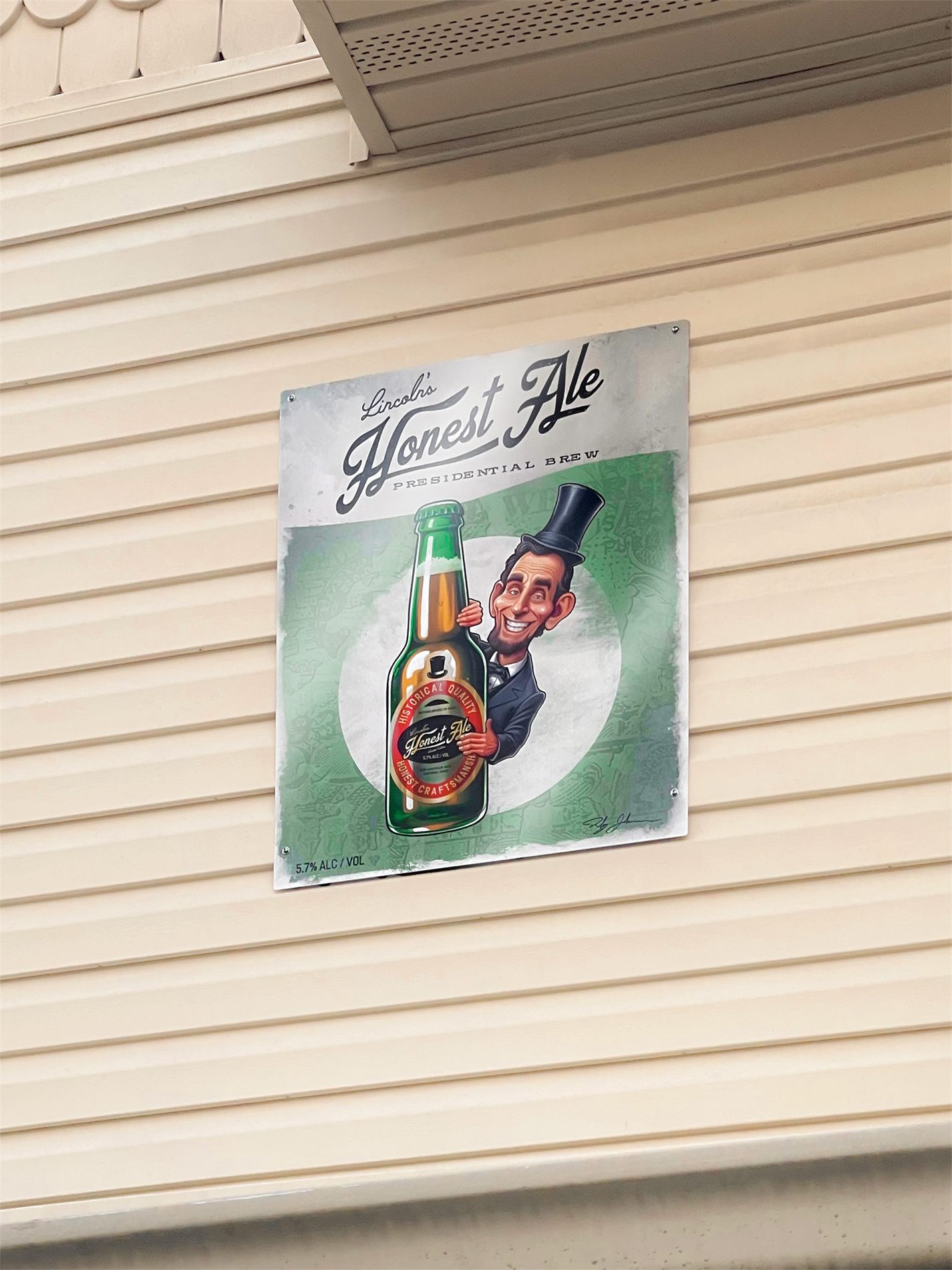 The hand-painted Lincoln's Honest Ale sign mounted on the cream siding of the house, with Abe Lincoln grinning from behind an oversized green bottle